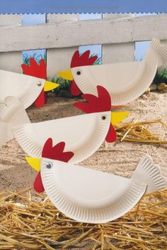 paper plates with chickens on them sitting in the sand next to some straw bales