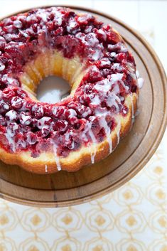 a bundt cake with white icing and cranberry topping on a wooden plate