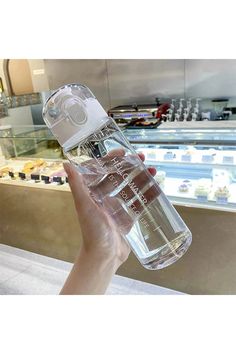 a person holding up a water bottle in front of a display case at a store