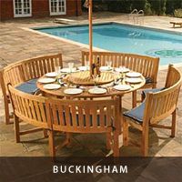 a wooden table sitting next to a swimming pool with an umbrella over the table and plates on it