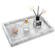 marble tray with gold accents and flowers on it, including a bottle of perfume next to a pink rock