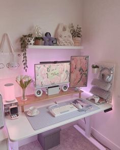 a desk with a computer monitor, keyboard and mouse on it in a pink room