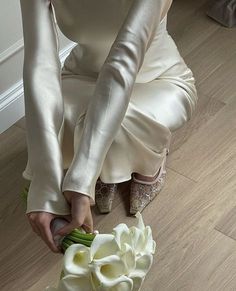 a woman kneeling down on the floor with flowers in her hand