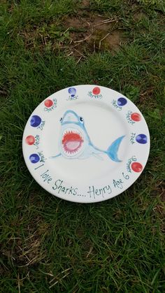 a plate with a shark on it sitting in the grass