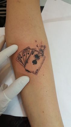 a person with a tattoo on their arm holding playing cards