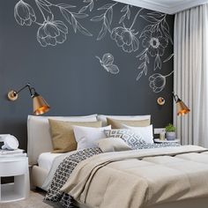 a bedroom with a bed, two lamps and a flower wall decal on the wall