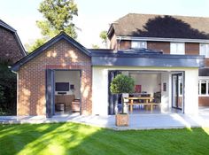 a house with an open patio and dining area in the back yard, surrounded by grass