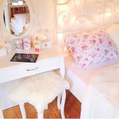 a bedroom with a white bed, vanity and mirror on the wall next to it