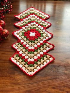 two crocheted christmas trees sitting on top of a wooden table