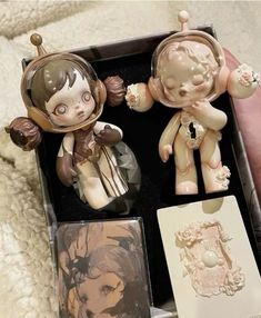 two small figurines are in a box