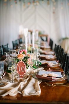 a long table is set with place settings and candles for an elegant dinner or party