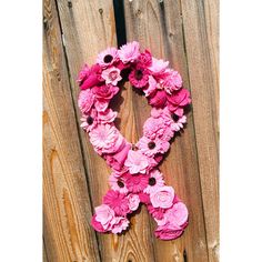 the letter k is made up of pink flowers on a wooden fence with a black ribbon