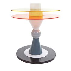 a glass table with an orange, yellow and blue top on it's base