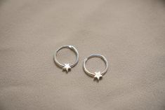 two small silver hoop earrings with stars on them