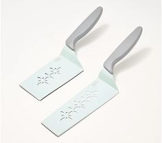 two plastic spatulas sitting on top of a white table next to each other