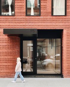 a woman walking past a tall brick building