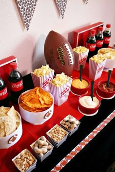 a football themed party with snacks, dips and crackers on a red table cloth