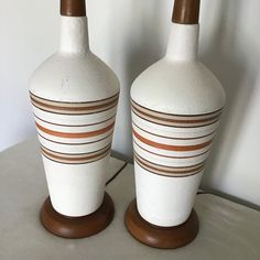 two white and brown vases sitting next to each other on top of a table