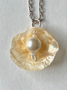 a necklace with a pearl in the center on a silver chain hanging from a white background