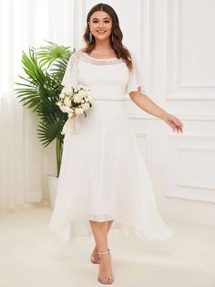 a woman wearing a white dress and holding a bouquet in her hand, posing for the camera