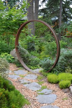 a circular metal object sitting in the middle of a garden