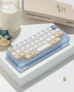 a blue and white keyboard sitting on top of a table next to a glass of milk