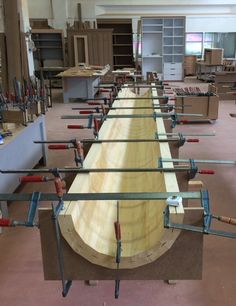 a long wooden table in a room with many tools on the tables and shelves behind it