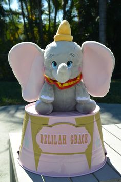 a stuffed elephant sitting on top of a pink and yellow box that says delta grace