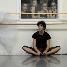 a young man sitting on the floor in front of a ballerina's reflection