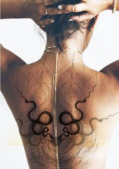 the back of a woman with tattoos on her upper and lower body, showing an intricate design