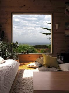 a bed sitting under a window in a bedroom next to a wooden wall and floor