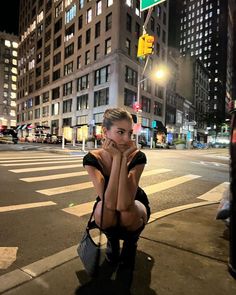 a woman sitting on the side of a street next to a traffic light