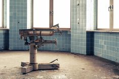 an old hospital room with blue tiles on the walls and floor, in front of a window