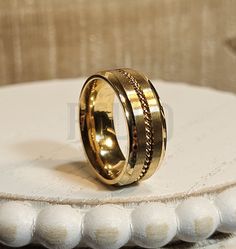 a gold wedding ring sitting on top of a white table