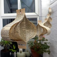 three paper lanterns hanging from a string with planters in the back ground behind them