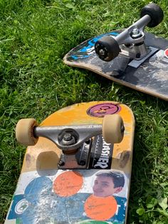 two skateboards laying on the grass with one upside down