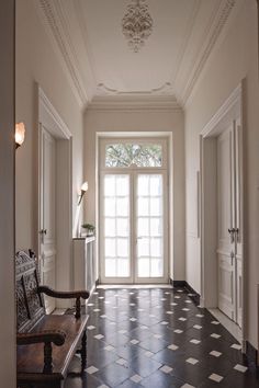 an image of a hallway with black and white tile on the floor, and a door leading to another room