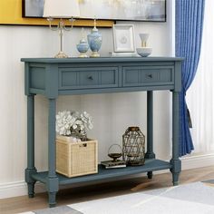 a blue console table with two drawers and a basket on the bottom shelf next to it