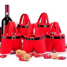 six red wine bags with santa's hats on them and two bottles of wine in the background