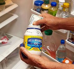 a person holding a bottle of hellamaine next to an open refrigerator with the caption'20 secret hiding places '