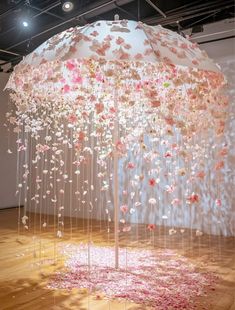 an umbrella that has been made out of flowers and is suspended from the ceiling with strings