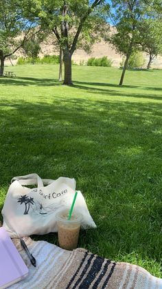 a bag sitting on top of a grass covered field next to a cup of coffee