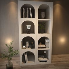 a white shelf with books and vases on it in a room that has wood flooring