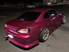 a purple car parked in a parking lot at night