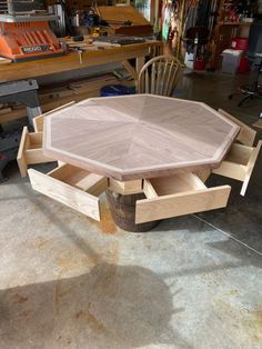 a wooden table sitting on top of a hard wood floor in a garage next to a workbench