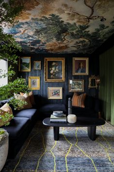 a living room filled with black couches and paintings on the wall next to a window