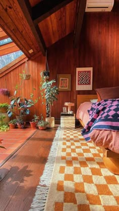 a bedroom with wooden walls and flooring has an orange checkered rug on the floor