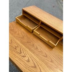 a wooden desk with three drawers on it's top and one drawer open to show the contents