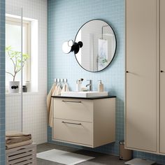 a bathroom with blue tiles and a round mirror