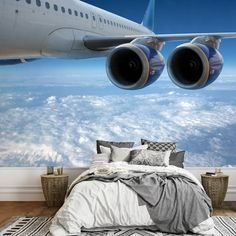 an airplane is flying over the clouds in this bedroom wallpapered with blue and white